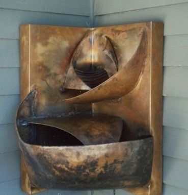 Copper water fountain mounted to an inside corner wall